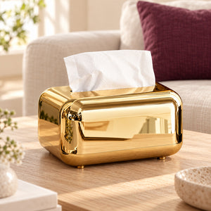 Gold mirror-finish tissue box with rounded corners on a wooden living-room coffee table