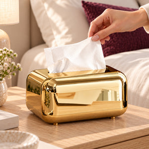 A hand lifting a tissue from the gold rounded tissue box on a bedroom bedside table